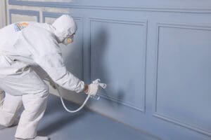 Painter for Baker Roofing and Construction providing residential painting services with a paint sprayer