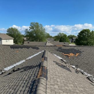 Hail-damaged roof in a suburban area highlighting the need for storm damage roofing services