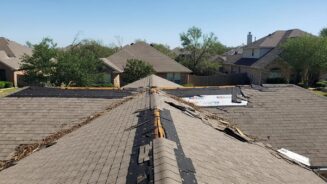 Roof showing storm damage in Texas neighborhood, emphasizing need for assessments by Baker Roofing and Construction